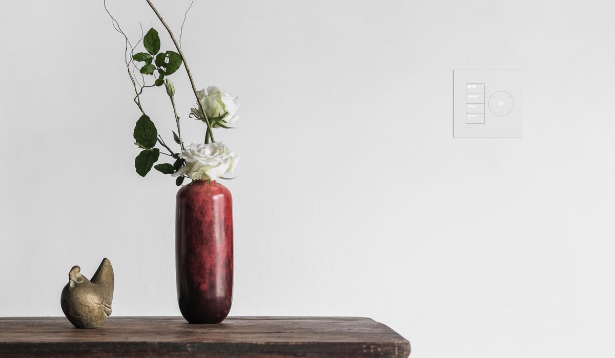 Joshai nano and lutron lighting keypad next to a wood table with a red vase