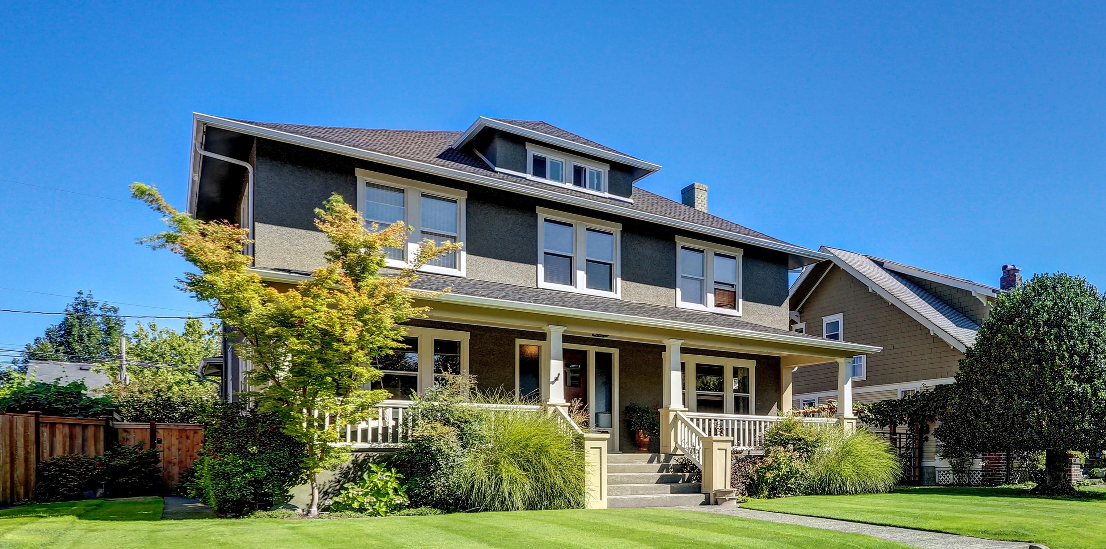 suburban home with a green lawn and native plants